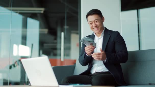 Szczęśliwy Sukces Azjatycki Biznesmen Liczy Fale Rzuca Pieniądze Biurze Patrząc — Wideo stockowe