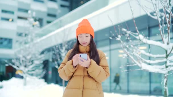 날씨에 거리에서 아름답고 소녀가 핸드폰 미소를 스마트폰을 메시지를 주고받는 여성입니다 — 비디오