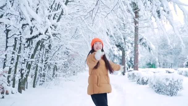 雪に覆われた冬の寒さの公園で楽しく踊る若い女性の幸せ 幸せよ アジアの女子学生ジャンプ雪の自然を背景に笑みを浮かべて歩く 喜んで スローモーション — ストック動画