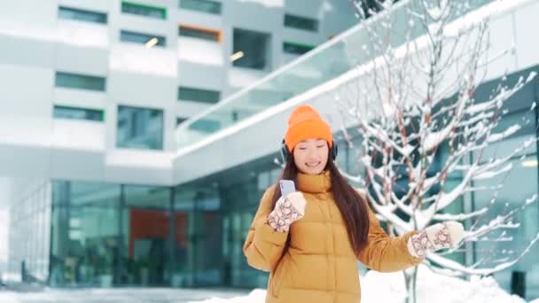 Young Beautiful Asian Woman Listens Music Headphones Walking Winter Snowy — Stock Video