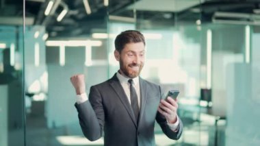 Mutlu, mutlu, mutlu, sakallı iş adamı. Mobil zaferi kutluyor, sevinçten havalara uçuyor. Şanslı yönetici iyi haberler alıyor.