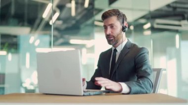 İş adamı yöneticisi internet kamerası ve kulaklık kullanarak çevrimiçi toplantı yapıyor. Modern ofis masasında dizüstü bilgisayarlı takım elbiseli bir ofis çalışanı. İş arkadaşlarınla, iş arkadaşlarınla konuş.