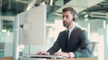 İş adamı yöneticisi internet kamerası ve kulaklık kullanarak çevrimiçi toplantı yapıyor. Modern ofis masasında dizüstü bilgisayarlı takım elbiseli bir ofis çalışanı. İş arkadaşlarınla, iş arkadaşlarınla konuş.
