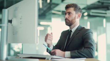 Modern bir ofis masasında bilgisayar üzerinde çalışan düşünceli bir erkek işadamı portresi. Takım elbiseli, dalgın, düşünceli bir iş adamı. Bir sorunu çözmek için ilham almayı düşünüyorum. Açılış