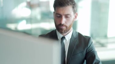 Modern bir ofis masasında bilgisayar üzerinde çalışan düşünceli bir erkek işadamı portresi. Takım elbiseli, dalgın, düşünceli bir iş adamı. Bir sorunu çözmek için ilham almayı düşünüyorum. Açılış
