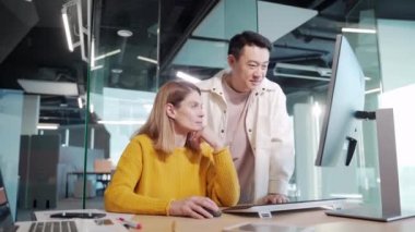 Modern ofisteki monitör ekranına bakarak bir projeyi tartışan yaratıcı insanlardan oluşan çok ırklı bir ekip. Sıradan Asyalı kadın ve erkek olarak iki genç iş arkadaşı.