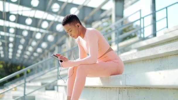 활동적 선수인 경기장에 양손에 스마트폰을 음악을 들으면서 여성에게 조깅을 휴식을 — 비디오