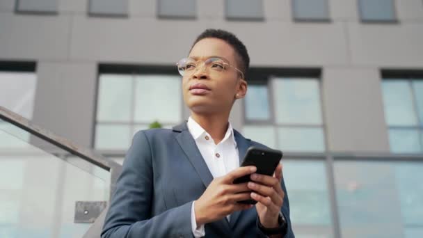 Думая Уверенная Деловая Афроамериканка Пользуется Смартфоном Мобильного Телефона Стоящим Рядом — стоковое видео