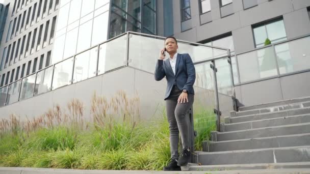 携帯電話で話している深刻なアフリカ系アメリカ人のビジネス女性 黒人女性起業家従業員は外でコミュニケーションをとる 眼鏡をかけたサラリーマンが話す 正式な訴訟の転換における実業家 — ストック動画