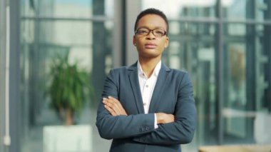 Kendine güvenen, ciddi, bağımsız Afro-Amerikan iş kadını modern ofiste kameraya bakıyor. Gözlüklü siyahi kadın girişimci. Uzman işçi kollarını kavuşturdu