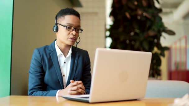 Mujer Afroamericana Seria Utiliza Auricular Para Una Videollamada Trabaja Café — Vídeos de Stock