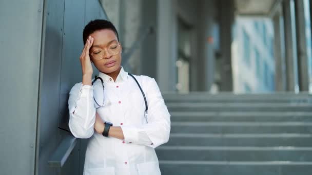 Εξαντλημένος Αγχωμένος Αφροαμερικανός Γιατρός Στέκεται Έξω Από Ένα Νοσοκομείο Κουρασμένος — Αρχείο Βίντεο