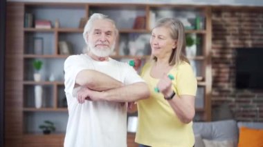 Kameraya bakan yaşlı, aktif, sportif, gri saçlı, emekli bir çiftin portresi. Mutlu Olgun Neşeli Aile Antrenmanı sırasında ayakta gülümsüyor. Emeklilikte sağlıklı yaşam tarzı