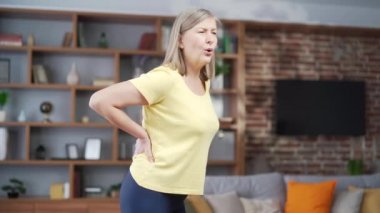 senior woman back pain at home. Worried upset mature female feel hurt sudden back ache. Upset eldery person suffering from backache, unhappy lady lumbar hurt in the spine or lower back in house
