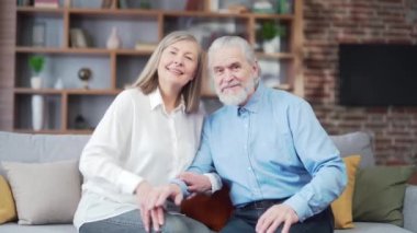 Web kamerası görüntüsü. Yaşlı çift görüntülü konuşma üzerinden iletişim kuruyor. Kameraya bakıyorum. Mutlu yaşlı insanlar aileleriyle konuşuyor, uzaktan iletişim kuruyorlar. Yaşlı karı koca evdeki kanepede oturuyor.