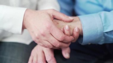 Yaşlı insanların ellerini kapayın. Yaşlı adam evde birlikte oturan bir kadının elini tutuyor. Yaşlı çift olgun aile koca ve büyük anne ve büyük baba birlikte evliliğe olan güveni destekliyor. Yakın çekim.