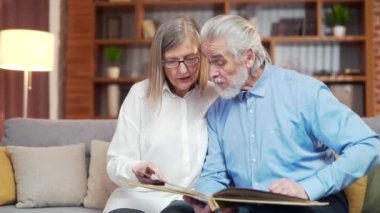 Evdeki kanepede Memoirs 'un fotoğraf albümünü izleyen harika bir son sınıf çifti. Yaşlı aile büyükbabaları birlikte oturup güzel anları tartışıyor. Sayfalar dolusu fotoğraf ve nostalji var.