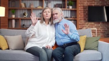Web kamerası görüntüsü. Yaşlı çift görüntülü konuşma üzerinden iletişim kuruyor. Kameraya bakıyorum. Mutlu yaşlı insanlar aileleriyle konuşuyor, uzaktan iletişim kuruyorlar. Yaşlı karı koca evdeki kanepede oturuyor.