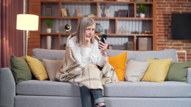 Sad Senior Gray Haired Woman Uses Phone While Sitting Home — стоковое видео