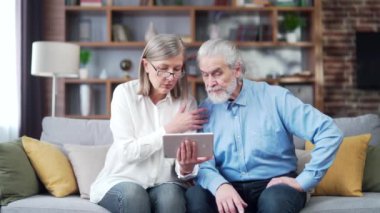 Yaşlı çift emekli oldu. Kadın ve erkek online danışmanlık videolarını izliyorlar. İki yaşlı hasta, evde uzaktan telefon kullanarak tavsiye veren bir doktor ya da avukatı dinliyor.