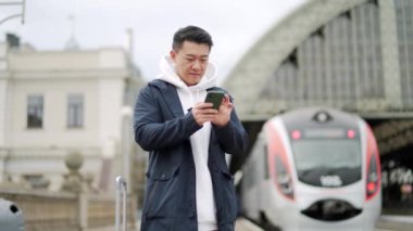 Asyalı turist konaklama yeri cep telefonuyla ayarlanıyor, yolcu trenle New City 'ye geliyor. Tren istasyonuna ve tren istasyonuna gelen yolcular. Yolculuktan önce akıllı telefon kullanın.