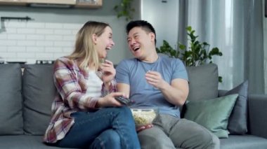 Neşeli bir aile ellerinde uzaktan kumandayla komik bir TV dizisi izlerken gülüyorlar. Asyalı genç çift, evde birlikte vakit geçirip komedi filmi izleyerek eğleniyorlar.