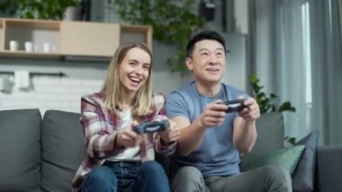 Neşeli evli çift ya da video oyunları oynayan arkadaşlar. Çok ırklı, mutlu bir aile evde birlikte vakit geçirir. Eğlenceli sevgili ve kız arkadaş joysticklerle gülüyor.