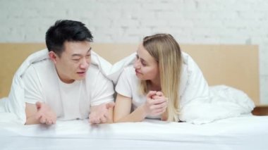 Mutlu, genç, çok ırklı aile yatakta yan yana yatıyor. Çift hafta sonları birlikte boş zaman geçirir sabahları. Neşeli Asyalı karı koca. Mutluluk ve şefkat, aşık insanlar.