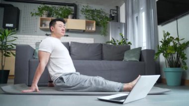Happy Asian evde yoga yapıyor, egzersiz yapıyor, spor yapıyor, antrenman yapıyor, bilgisayarını online dersler için kullanıyor, aktif bir yaşam tarzı uyguluyor. dizüstü bilgisayar öğrenme derslerini izle