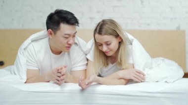 Mutlu, genç, çok ırklı aile yatakta yan yana yatıyor. Çift hafta sonları birlikte boş zaman geçirir sabahları. Neşeli Asyalı karı koca. Mutluluk ve şefkat, aşık insanlar.