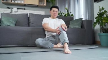 Asyalı bir adam diz ağrısı, bacak kasları ve evde romatizmadan muzdarip. Sporcu erkek hastalıkları krampları, eklem ağrıları. Sağlık hizmeti. Antrenmandan sonra ya da evde egzersiz yaparken masaj.