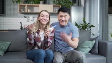 Mutlu çok ırklı çift kameraya bakarak hamilelik testi sonucunu gösteren bir video görüşmesinde iyi haberleri paylaşıyor. Melez ailelerin gelecekteki aileleri anlatıyor ve gösteriyor. Web kamerası görünümü