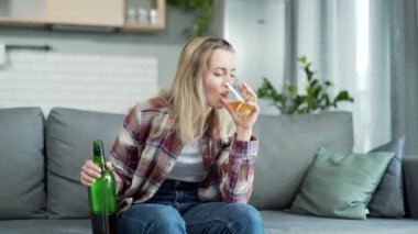 Kadın alkolizmi. Evde yalnız bir kadın elinde bir bardak viskiyle kanepede oturuyor ve alkol içiyor. Üzgün keder genç alkolik kadın evde. bağımlılık sorunu kavramı