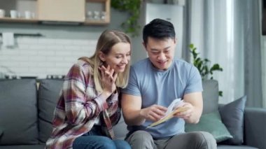 Aile, iyi haberlerle dolu bir mektup ya da mesaj alır. Mutlu bayramlar. Asyalı çift, evde oturmaktan mutluluk duyan bir belge alıyor. Neşeli karı koca kitap okurken gülümsüyor.