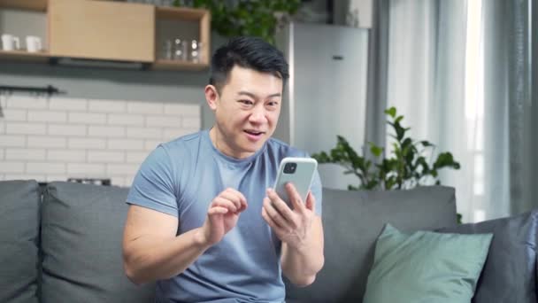 휴대폰을 기뻐하는 남자는 집에서의 승리로 충격을 받았습니다 스마트폰 화면을 환호하는 — 비디오