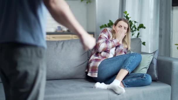 家庭暴力 男人和女人吵架 愤怒的丈夫坐在沙发上哭泣着殴打妻子 打架的夫妻在家里吵架打斗的夫妻 — 图库视频影像