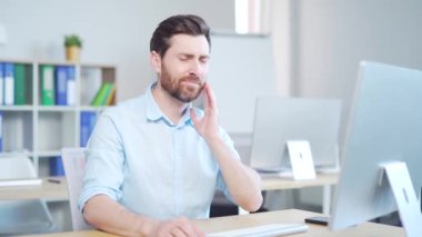 Genç, sakallı, beyaz, dişleri ağrıyan bir adam. Erkek işçi içeride şiddetli acıdan muzdarip. İş yerinde işyerinde oturmak. Dişlerinde acı veren diş hastalığı