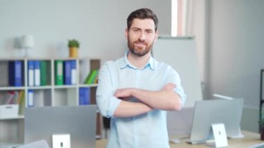 Yakışıklı, beyaz sakallı bir ofis çalışanının portresi, kameraya bakıp gülümseyen bir girişimcinin çalışanı. İşte mutlu ve neşeli bir erkek katip. Modern bir iş yerinde iş adamı.