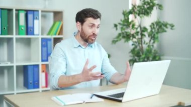 Öfkeli ofis çalışanı bağırıyor ve online tartışmalar yapıyor iş arkadaşlarıyla veya müteahhitlerle görüntülü görüşme yapıyor. Ofisteki dizüstü bilgisayarla web kamerasıyla iletişim kuruyor. Sinirli erkek çalışan