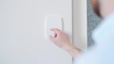 Adam kapıyı açmak için güvenlik şifresine basıyor. İşadamı parmak şifresi kodunu alarm paneline giriyor, erkek kolunu içeride kapatıyor. Ofis binası, apartman.