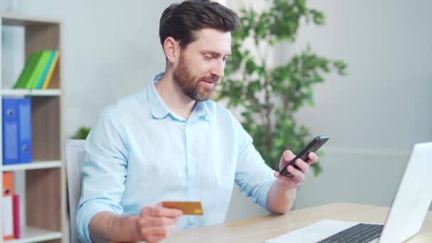 快乐男人在网上购物用信用卡支付使用手机 智能手机坐在写字台 在工作 采购旅行 银行服务 工作场所临时工中的男性自由职业者 — 图库视频影像