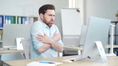 Ofis çalışanı ofiste dondu kaldı. Erkek Girişimci, iş yerinde üşümüş vaziyette. İş yerindeki düşük sıcaklık yüzünden kendini rahatsız hisseder. Soğuktan acı çeken bir adam.. 