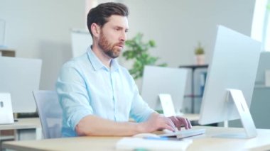 Bilgisayarda araştırma yapan odaklanmış sakallı iş adamı girişimci. Modern ofis masasında bilgisayar kullanan genç bir profesyonel. Modern teknoloji defteri üzerinde çalışan meşgul bir işçi.