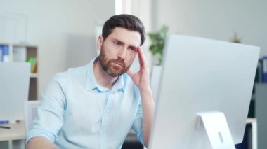 Odaklanmış yakışıklı sakallı iş adamı ofisteki bilgisayar monitörüne ya da laptopa bakıyor. Düşünceli bir girişimci, akıllı tesadüfi bir şekilde kapalı alanda arama yapıyor.