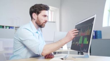 Confident business man stocks broker sitting in front of monitor screen in office analyzing stat of index charts data analyses market trend. Forex trading agency worker agent reviewing profits growth