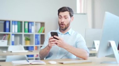 Mutlu ve mutlu sakallı iş adamı mobil zaferini kutluyor, çok sevinçli yönetici kazananı iyi haberler alıyor. Akıllı telefonu kullan. Finansal başarı için bahse gir.