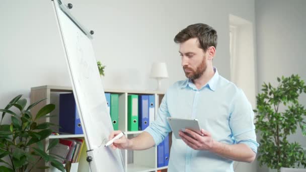 重点员工在白板上绘制图表 金融分析师商人站在白板前 分析图表 商业策略 启动时手里拿着平板电脑 — 图库视频影像
