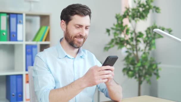 Šťastný Pohledný Kancelářský Pracovník Sedící Počítačového Stolu Kanceláři Pomocí Mobilního — Stock video