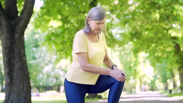 长跑者肌肉疼痛 成熟的老妇人在室外慢跑时按摩 健康的女性扭伤严重拉伤 腿肌肉痉挛小腿运动训练伤了腿膝盖 — 图库视频影像