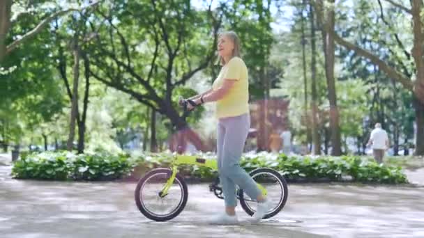 Glad Äldre Mogen Modern Aktiv Kvinna Promenader Med Cykel Stadsparken — Stockvideo
